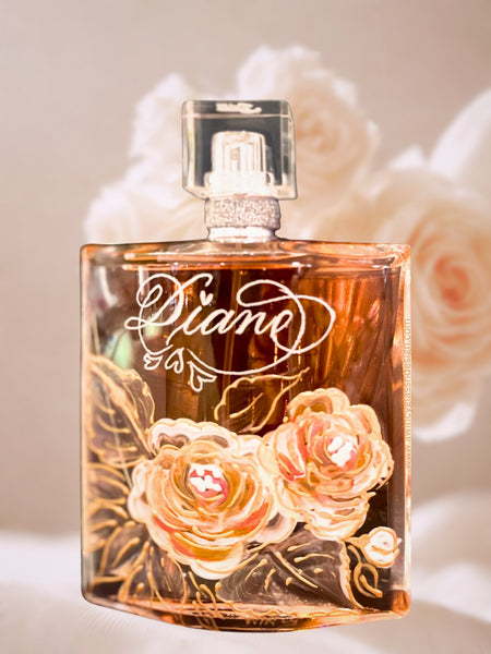 Engraved and hand-painted Lancome La Vie Est Belle perfume bottle featuring delicate peach florals on clear glass, surrounded by a soft floral bouquet — a luxury personalized gift for brides, bridesmaids, and mothers of the bride, crafted by A Wincy Glass ’N Design