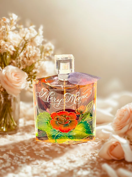 Lancome La Vie Est Belle perfume bottle engraved and hand-painted with a deep red cabbage rose and green leaves, outlined in raised gold detailing — a personalized perfume bottle perfect for brides, anniversaries, or other meaningful celebrations, handcrafted by A Wincy Glass ’N Desig