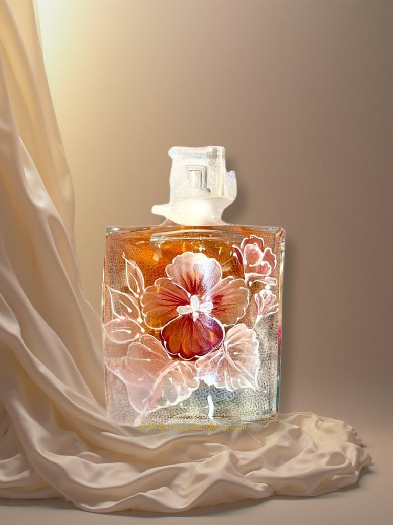 Closeup of a Lancome La Vie Est Belle perfume bottle hand-painted with pink and silver shimmer pansy florals — a luxury personalized perfume bottle for brides, bridesmaids, and mothers of the bride, crafted by A Wincy Glass ’N Design