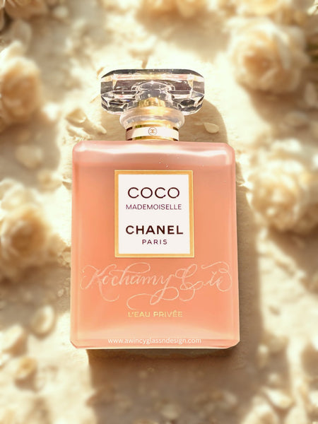 Personalized engraved Chanel-style perfume bottle,” set on a flat surface with a soft, blurred bed of pale roses in the background; elegant bridal editorial aesthetic; ideal gift for brides, bridesmaids, and proposal boxes.
